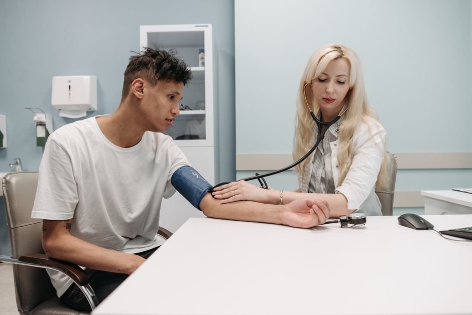A clinician measuring a man's blood pressure with a cuff during a routine visit