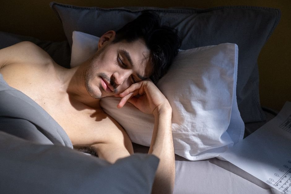 A man sleeping in a sunlit bedroom, illustrating sleep apnea in men explained and the importance of restful sleep